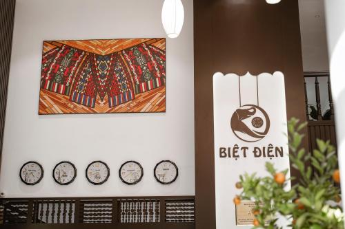 a group of clocks on a wall with a picture at Biet Dien Hotel in Buon Ma Thuot