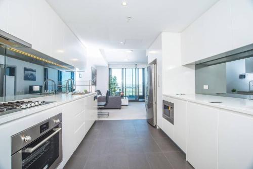 a kitchen with white cabinets and a living room at Minimalism modern apartment*waterview*parking＊IGA in Sydney