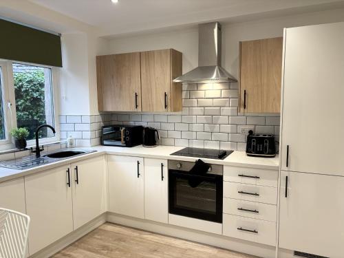 a kitchen with white cabinets and a stove top oven at Hardy Hideaway in Ulverston