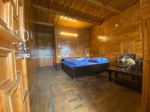 um quarto com uma cama azul num chalé de madeira em Kiran Home Stay em Shoja