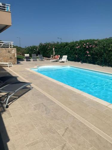 - une piscine avec des chaises et une personne assise à côté dans l'établissement Grand appartement T4 - piscine - vue féérique, à Propriano