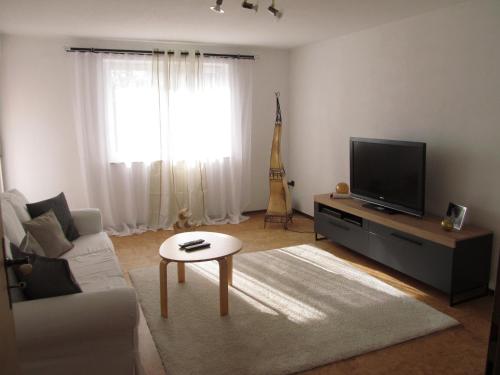 un salon avec un canapé blanc et une télévision dans l'établissement Ferienwohnung Bluhm, à Weilheim in Oberbayern