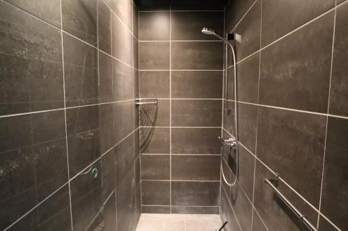 La salle de bains est pourvue d'une douche et de murs carrelés bruns. dans l'établissement Schellerup Gård, à Herning