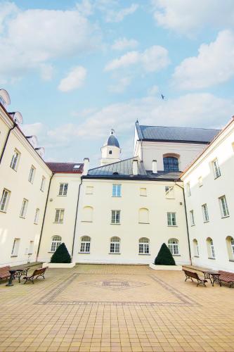 a large white building with benches in a courtyard at Domus Maria in Vilnius