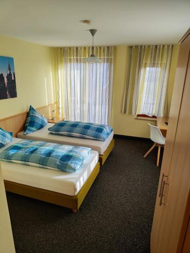 a hotel room with two beds and a desk at Wirtshaus Zur Bina in Vilsbiburg