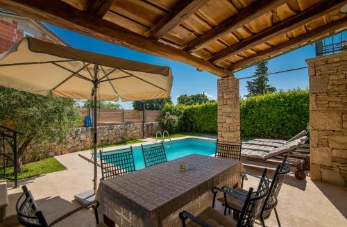a patio with a table with an umbrella and a swimming pool at Villa Pinia with pool in Pinezici