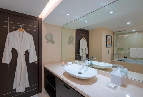 a bathroom with a sink and a robe hanging on a door at Hyatt Regency Galleria Residence Dubai in Dubai