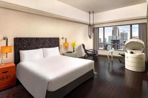 a bedroom with a white bed and a desk and a window at Sofitel Saigon Plaza in Ho Chi Minh City