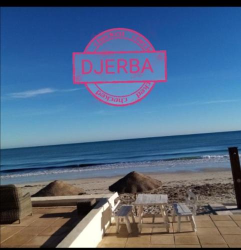 El Maamoura的住宿－H.younes，海滩上的标志,配有桌椅
