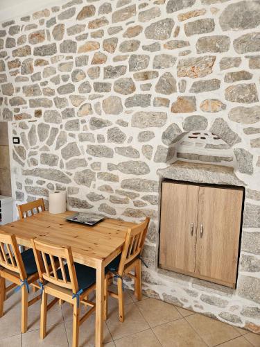 a wooden table and chairs in front of a stone wall at Rigas stone tower east Mani 2 in Agriliá