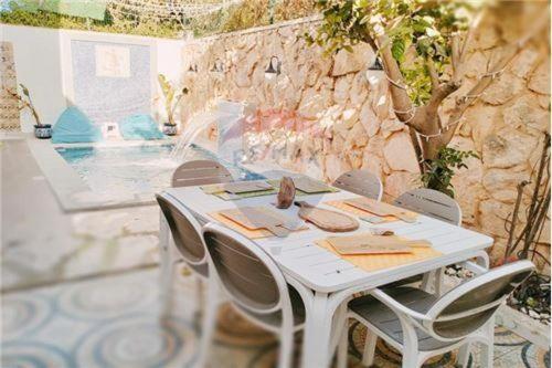 una mesa blanca y sillas en un patio con piscina en H.younes en El Maamoura