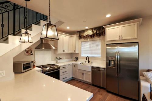 cocina con armarios blancos y nevera de acero inoxidable en Modern comfort, prime location, 360 views, 4 BR entire house, en San Diego