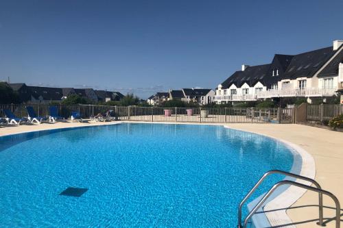 une grande piscine bleue avec des chaises et des maisons dans l'établissement Appartement A22, à Arzon