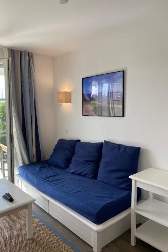 - un canapé avec des oreillers bleus dans le salon dans l'établissement Appartement A21, à Arzon