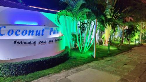 a building with a sign for a swimming pool and fence at Coconut Palms in Kantharawichai