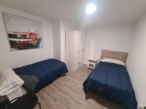 1 dormitorio con 2 camas y una pintura de coche en la pared en Piso lujo 2 habitaciones (1), en Las Rozas de Madrid