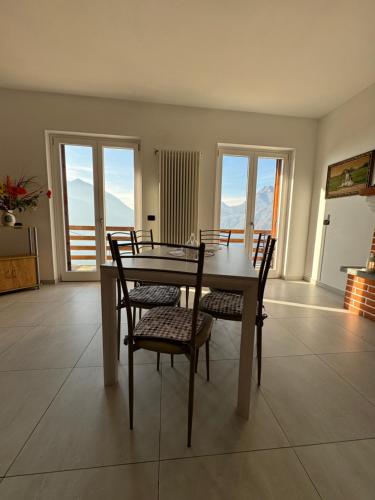 a dining room with a table and chairs and windows at Villa Bianca in Varenna