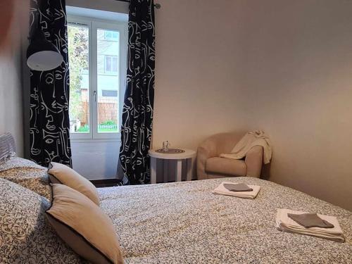 une chambre avec un lit, une chaise et une fenêtre dans l'établissement L’Oasis Fleuri, à Bourg-de-Péage