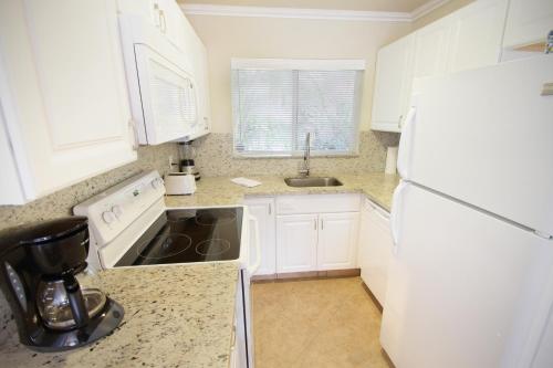 a kitchen with white cabinets and a white refrigerator at Casitas Coral Ridge in Fort Lauderdale