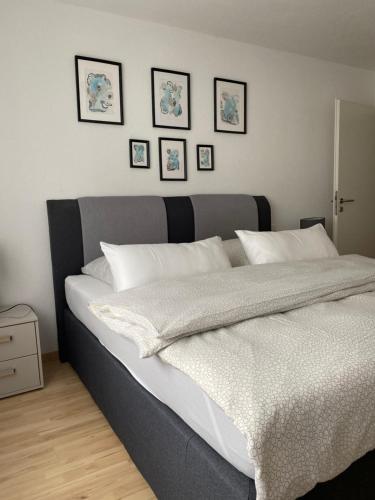 een slaapkamer met een groot bed met vier foto's aan de muur bij Gemütliches City Apartment in Friedrichshafen