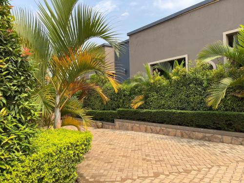 a brick walkway with palm trees and a building at Ashleys Hotel in Kampala