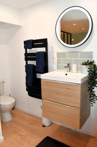 une salle de bain avec un lavabo et un miroir dans l'établissement L'amour à la plage, à Deauville