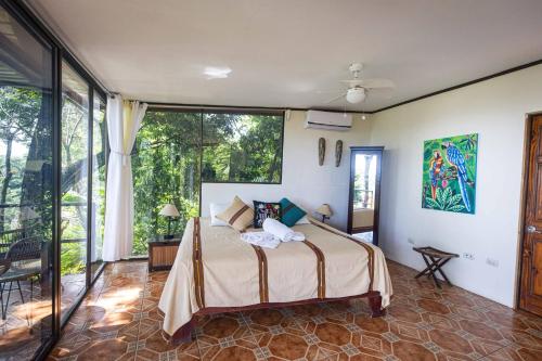 a bedroom with a bed and a large window at Mango Moon Villa in Manuel Antonio
