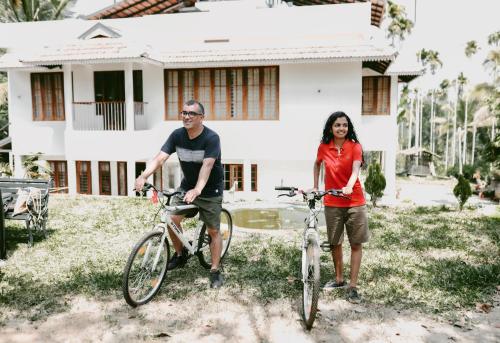 a man and a woman standing with their bikes in front of a house at Ananda Holiday Home in Ambalavayal