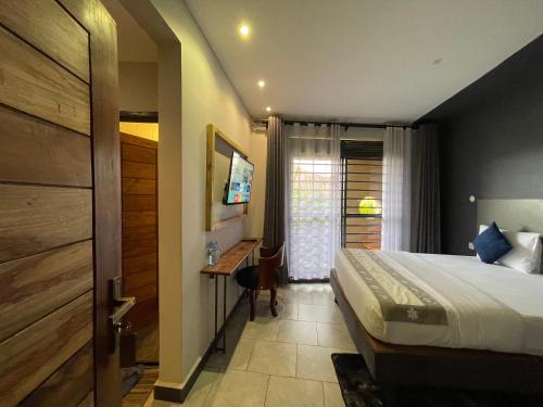 a bedroom with a bed and a desk and a window at Ashleys Hotel in Kampala