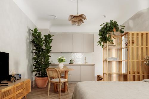 a bedroom with a bed and a kitchen with plants at Spīdalas nams in Cēsis