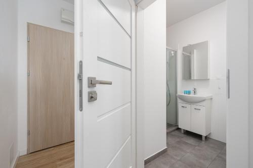 eine weiße Tür im Bad mit Waschbecken in der Unterkunft Potulicka Comfort Studio in Stettin