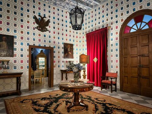 a living room with a table and a red curtain at Palazzo Arone dei Baroni di Valentino in Palermo