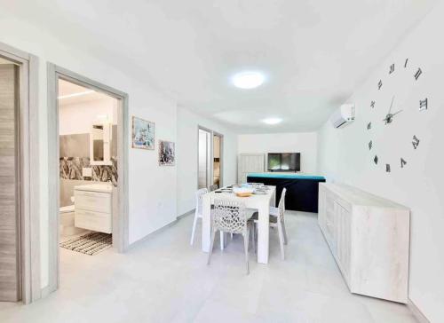 cocina blanca con mesa y comedor en Best in Villasimius: modern, perfectly located, en Villasimius