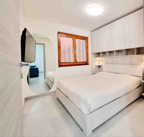 1 dormitorio blanco con 1 cama grande y espejo en Best in Villasimius: modern, perfectly located, en Villasimius