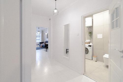 a white hallway with a door to a laundry room at Glow Apartments, Apartamenty Śródmieście in Gdańsk