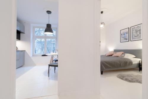 a white bedroom with a bed and a window at Glow Apartments, Apartamenty Śródmieście in Gdańsk