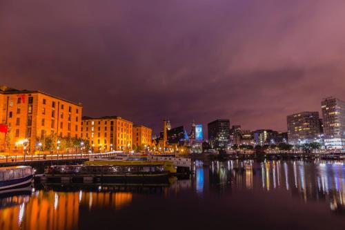 a city skyline at night with boats in the water at Maldron Hotel Liverpool City Centre in Liverpool