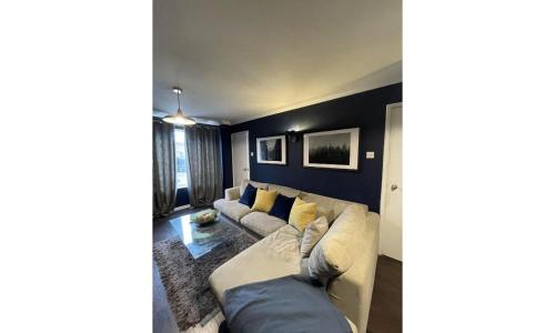 a living room with a white couch and yellow pillows at Shortlet Express, Stylish 3 Bedroom house in Hatfield in Hatfield