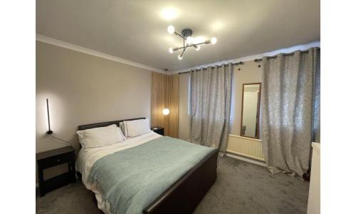 a bedroom with a large bed and a window at Shortlet Express, Stylish 3 Bedroom house in Hatfield in Hatfield