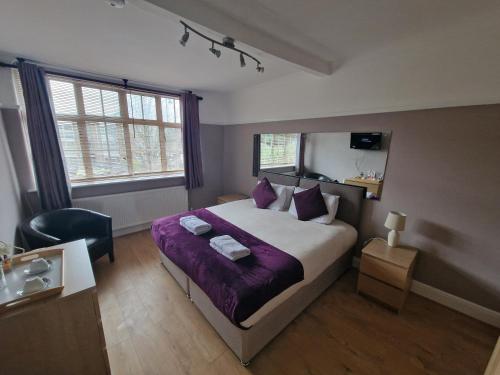 a bedroom with a large bed with a purple blanket at Kathleen House in Enfield