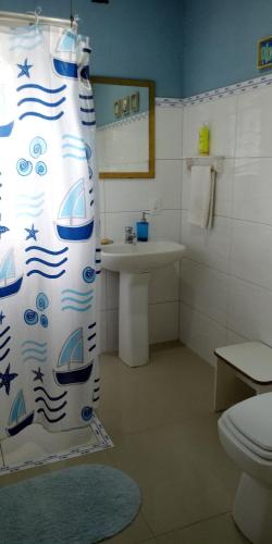 a bathroom with a shower curtain with a sink and a toilet at Quarto na Praia de Taquaras in Balneário Camboriú