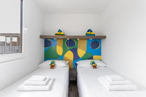 two beds in a room with a colorful wall at Club del Sole Romagna Family Resort in Riccione