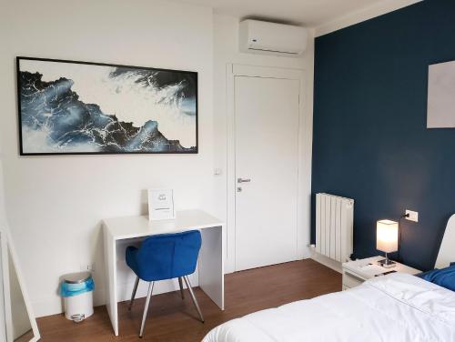 ein Schlafzimmer mit einem Bett und einem Schreibtisch mit einem blauen Stuhl in der Unterkunft Next Rest B&B in Selargius