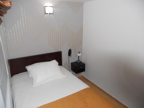a small bedroom with a white bed and a lamp at Hotel Expo Inn Embajada in Bogotá