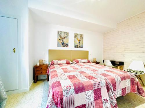 a bedroom with a bed with a red and white quilt at Hostal La Taberna in Arenas de San Pedro