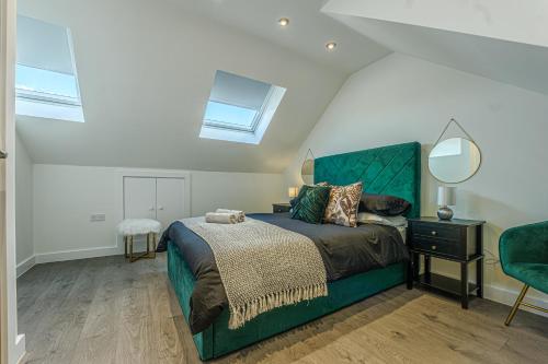 een slaapkamer met een groen bed en een spiegel bij Stylish & Central Homes in Bromley in Bromley