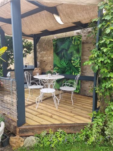 a patio with a table and chairs on a wooden deck at La Bar La Bonne in Barbonne-Fayel