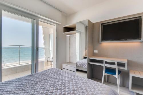 a bedroom with a television and a bed with a desk at MARITTIMO Riccione - H Clipper in Riccione