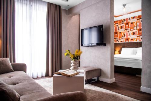 un soggiorno con divano, TV e letto di CRYSTAL Hotel Belgrade a Belgrado