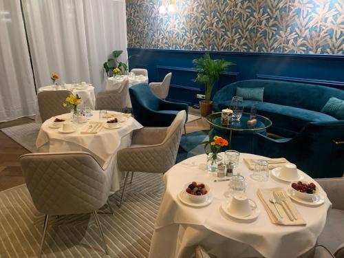 un restaurant avec des tables et des chaises blanches et un canapé dans l'établissement La Cabane D'Ambroise, à Bordeaux